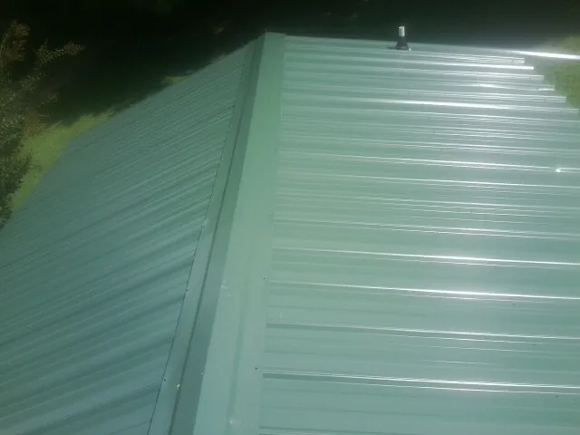 New green metal panels meeting at the ridge of a roof — Flat Roof Repair work by our crew in Hawley