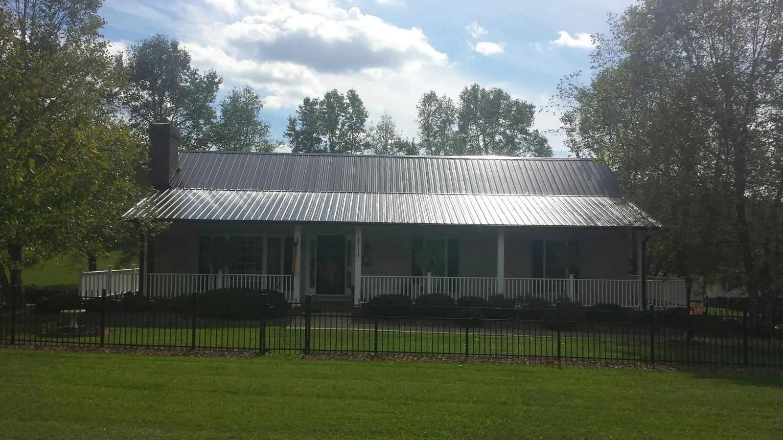 Gray metal roof on a brick ranch with a full width front porch — Gutter Guard Installation work by our crew in Hawley